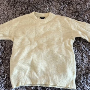 Ljusgul stickad tröja från Lindex - Mysig ljusgul stickad tröja från Lindex med rund hals och ribbade muddar vid ärmslut och nederkant. Perfekt för att addera lite färg till din garderob. Enkel och stilren design som funkar till många olika looks.