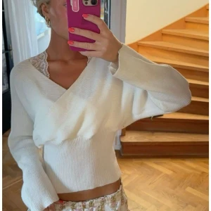 Vit omlottstickad topp 🩷 - Superfin vit stickad tröja med omlott-design och v-ringning. Tröjan har långa ärmar och ribbad nederkant, perfekt för lager-på-lager. Snygg och enkel att matcha med både jeans och kjol.