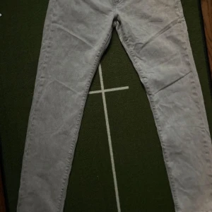 Levi's 502 grå jeans W29 L32 - Snygga grå Levi's 502 jeans med klassisk femficksdesign och rakt snitt. Jeansen har en diskret tvättad look och är tillverkade i mjukt bomullstyg. Perfekta för dig som gillar en stilren och avslappnad vibe.