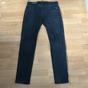 Replay Anbass jeans  - Svarta Replay Anbass jeans i slim fit med klassisk femficksdesign. Jeansen har en snygg, smal passform och är tillverkade i stretchigt bomullsmaterial för extra komfort. Perfekta för dig som gillar stilrena och moderna jeans.