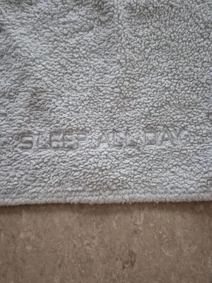Tröja - Mysig grå fleece-tröja från Cubus i storlek S. Tröjan har lång ärm och är tillverkad i 100% polyester. På framsidan finns broderad text 'SLEEP ALL DAY' som ger en chill vibe. Perfekt för slappa dagar hemma när du vill vara extra bekväm.