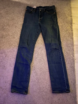 Levi's 501 blå jeans straight fit - Klassiska Levi's 501 jeans i mörkblå denim med raka ben. Snygga kontrastsömmar och ikonisk läderpatch baktill. och straight passform/slim fit perfekt för en chill och tidlös look.