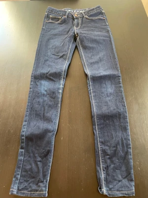 Mörkblå skinny jeans - Snygga mörkblå jeans med klassisk femficksdesign och kontrastsömmar. Modellen är skinny med låg midja och tillverkad i stretchigt jeansmaterial för en schysst passform. Perfekt för dig som gillar en smal siluett och stilren look.