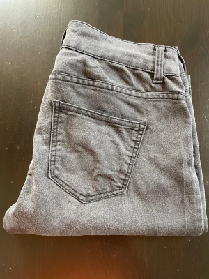 Grå jeans med rak passform - Snygga grå jeans med klassisk femficksdesign och rak passform. Jeansen har bälteshällor och knappstängning framtill. Materialet är mjukt och bekvämt denim, lite stretch, som passar perfekt till en avslappnad stil. Färgen är neutral och lätt att matcha med olika outfits.   Strl M, mått midja tvärs över 35 cm innerben 81 cm