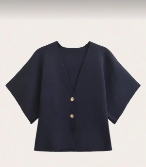 Mörkblå kofta med kort ärm - Snygg mörkblå kofta med v-ringning och två knappar framtill. Modellen har korta, vida ärmar och en loose passform som ger en chill och modern vibe. 