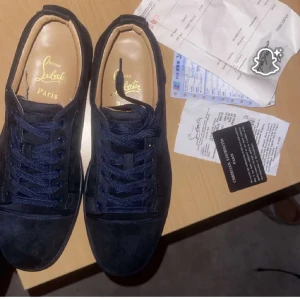 Mörkblå sneakers från Christian Louboutin - Snygga mörkblå sneakers från Christian Louboutin i mocka med klassisk rund tå och platt sula. Skorna har matchande mörkblå snörning och exklusiv känsla med märkets logga i guld på innersulan. Perfekta för dig som vill sticka ut med stil.