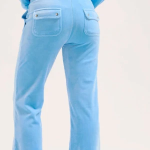 Ljusblå velourbyxor Juicy Couture - Pris diskuteras! Supermjuka ljusblå velourbyxor från Juicy Couture med snörning i midjan och stora fickor fram och bak. Byxorna har en relaxed passform och raka ben, perfekta för en chill och trendig look.