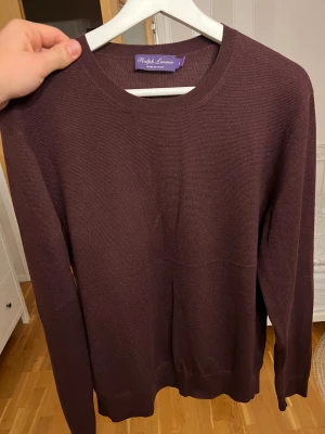 Ralph Lauren Purple label Kashmir/ silke tröja  - Säljer nu en av mina exslusivaste plagg, en Kashmir/ silke tröja.  Purple Label är Ralph Laurens mest exklusiva linje, känd för sin höga kvalitet. Tröjan är i princip i nyskick, det finns inga tecken på använding och är ett plagg som visar på italienskt hantverk i högsta grad. Tröjan är i storlek L men kan också passa M. Tröjan är i färgen vinröd men blir lite svårt att få den riktiga färgen på bild nu i kvällsmörkret.  Loro piana, brunello cucinelli, Kiton, Isaia, Zegna. Nypris $795= 7700SEK