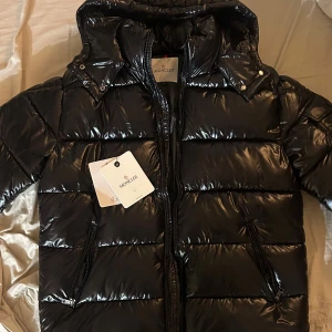 Svart Moncler Maya i stl 4 - Säljer en svart Moncler Maya i stl 4 (L) då den inte passar mig och behöver jacka nu när det är kallt akut därför är priset hyfsat bra för att vara helt nya. Vid snabb affär kan priset självklart diskuteras. Skriv gärna för mer bilder :)