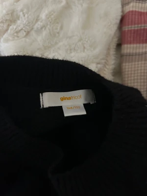 Svart stickad tröja - Svart stickad tröja från Gina Tricot med broderade stjärnor i silver på framsidan. Tröjan har rund hals, långärmade och en loose passform som ger en chill vibe. Perfekt att matcha med jeans eller kjol för en cool look.