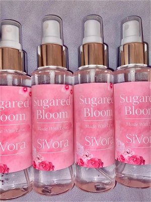 Sugared Bloom Body Mist - Snygg rosa flaska med blommigt tema. Perfekt för dig som vill ha en söt och fräsch vibe. Flaskan har texten 'Made With Love' och passar dig som gillar unika detaljer. Volym och ingredienser syns ej på bilden.