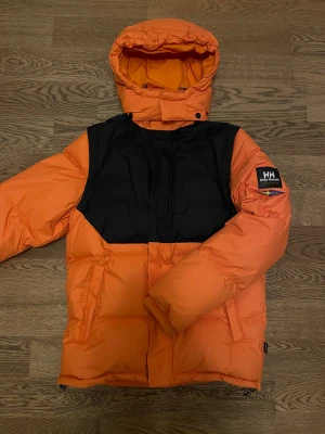 Helly Hansen x Sweet Sktbs Pufferjacka - Unik orange Helly Hansen x Sweet Sktbs pufferjacka. Varsamt använd, som ny. Säljs pga minskad användning. Bara att höra av dig vid intresse, frågor eller önskan om fler bilder!
