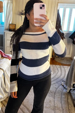 Randig stickad tröja i marinblått och vitt - Säljer en snygg stickad tröja med breda marinblå och vita ränder. Tröjan har lång ärm och en rak, något bredare halsringning. Passformen är normal och materialet känns mjukt och skönt mot huden. 