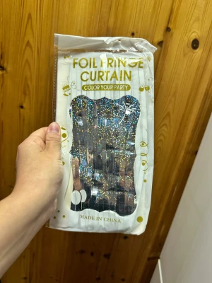 Foil Fringe Curtain girlang dörr eller vägg draperi  - Glittrig folie-gardin perfekt för festdekoration. Produkten är ny och förpackad, med holografisk effekt som ger extra glans till din fest. Enkel att hänga upp och passar till födelsedagar, bröllop och andra firanden. Inga synliga defekter eller slitage. Ca: 1 m bred, 2 m lång