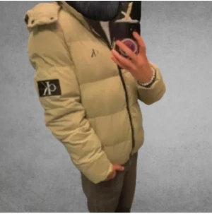 Beige pufferjacka från Calvin Klein - Snygg beige pufferjacka från Calvin Klein med svart CK-logga på bröstet och ärmen. Mycket varm och skön. Inga defekter bra skick storlek xs. Skicka om minsta fundering. 
