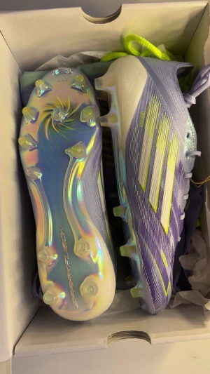Elite Adidas F50 Lila fotbollsskor - Säljer ett par Adidas F50 elite fotbollsskor i lila med neon-gula och vita detaljer. Skorna är använda 1 gång i ca 30 min och har inga defekter eller tecken på användning. Skornas nypris var 2945kr. Storleken är unisex 38 2/3. Du får skolådan och gympapåsen med skorna!