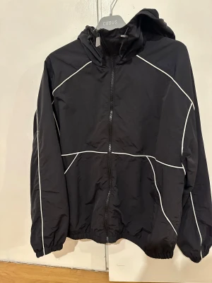 Svart vindjacka med vita detaljer - Svart vindjacka från Bershka, oanvänd