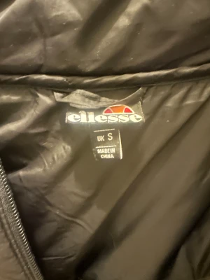 Ellesse dunväst svart och grön S - Snygg dunväst från Ellesse i storlek S. Västen är svart upptill och mörkgrön nedtill, har hög krage och dragkedja framtill. Quiltad design med Ellesse-logga på bröstet. Knappt använd bara provad.