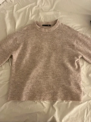 Beige stickad tröja från Lager 157 XS - Mysig stickad tröja i beige från Lager 157, storlek XS. Tröjan har en rund halsringning. Perfekt för dig som gillar enkel och clean stil med en neutral färgpalett.