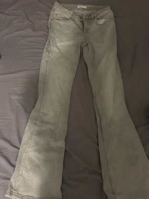 Grå bootcut jeans från Perfect Jeans - Snygga grå jeans från Perfect Jeans i bootcut-modell. Jeansen har klassisk femficksdesign, normalhög midja och är tillverkade i ett mjukt jeanstyg. Perfekta för dig som gillar en retroinspirerad look med utsvängda ben.