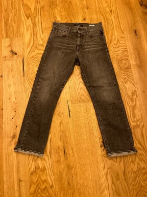 Replay svarta jeans straight fit - Säljer ett par svarta Replay jeans med klassisk femficksdesign och raka ben. Jeansen har snygga slitningar framtill och bak, samt Replay-logga på bakfickan. Passformen är straight och materialet är robust denim. Perfekt för dig som gillar en enkel och cool stil.