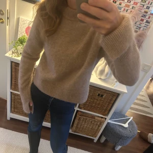 Ny ull & mohair Beige stickad tröja från H&M Stl s - Ny  beige stickad tröja från H&M i mohair- och ullblandning. Tröjan har en klassisk rund halsringning, ribbade muddar och lång ärm med sluts nedtill .Perfekt för lager på lager under kyliga dagar.