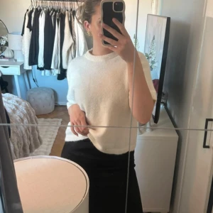 Vit stickad kortärmad tröja - Säljer en vit stickad tröja med korta ärmar och rund hals. Tröjan har en mjuk och enkel design som är lätt att matcha med olika outfits. Från gina tricot.