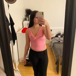 Rosa offshoulder topp  - Säljer en ljusrosa croppad topp med omlott-drapering fram och bak. Toppen är ärmlös och har en snygg, lös passform som kan stylas offshoulder. Materialet känns mjukt och stretchigt, troligen polyester eller bomull. Perfekt för dig som gillar trendiga och bekväma plagg.