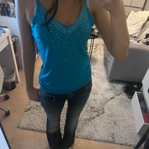 Blå linnetopp med diamanter - Snygg blå linnetopp med smala axelband och v-ringning. Toppen har diamanter framtill som ger en extra touch. 💎🦋💙