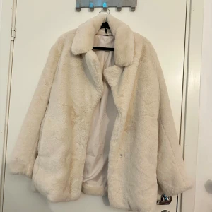 Beige pälsjacka från H&M Divided - Fluffig och oversized pälsjacka i beige från H&M Divided. Jackan har bred krage, långärmade ärmar och mjukt foder. Perfekt för dig som vill ha en mysig och trendig look under höst och vinter. Snygg att styla med jeans eller klänning.