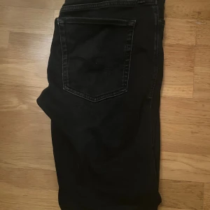 Svarta jeans Comfort Mike Jack & Jones - Svarta jeans från Jack & Jones, modell Comfort Mike. Klassisk femficksdesign med raka ben och normal passform. Jeansen är tillverkade i ett mjukt och slitstarkt bomullsmaterial som ger en skön känsla hela dagen.