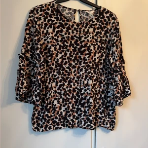 Leopardmönstrad blus från Object - Säljer en snygg blus från Object i storlek 42 med leopardmönster i svart, beige och brun. Blusen har rund hals, trekvartsärm med volangdetalj och ett litet knappslå i nacken. Materialet är lätt och luftigt, perfekt för dig som gillar att sticka ut.liten i st mer en M.