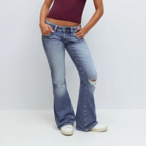 Blå bootcut jeans med broderi - Snygga blå jeans från Gina Young med bootcut passform och låg midja. Jeansen har slitna detaljer vid knäna och coolt rött broderi på bakfickorna. Används ej längre och är knappt använda men kan va lite lite slitna vid slutet pågrund av att de va för långa💞