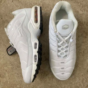 Nike Air Max vita sneakers strl 42 - Nike Air Max sneakers i helvit färg med svarta detaljer på sulan. Skorna har en chunky siluett, synlig Air-enhet i sulan och mönstrad mesh samt syntetpaneler. Klassisk snörning och rund tå. Perfekt för dig som gillar sportig och clean stil.