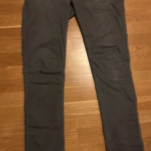 Grå Acne Studios Max Darko jeans - Snygga grå jeans från Acne Studios, modell Max Darko. De har en smal passform med klassisk femficksdesign och dragkedja i gylfen. Materialet är 98% bomull och 2% elastan för extra stretch och komfort. Perfekta för dig som gillar stilrena och moderna jeans.
