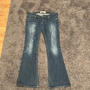 Lågmidjade bootcut från Hollister - Bootcut jeans från Hollister i mörkblå tvätt! De ser ljusare ut på bilden än i verkligheten! Passar xs/s, är dock lite korta i benen! Har en slitning i vänster ben (se bild 3) men inget som stör! Köpta för 700!💕