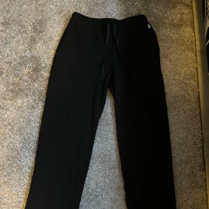 Svarta mjukisbyxor från Polo Ralph Lauren - Svarta mjukisbyxor från Polo Ralph Lauren med klassisk broderad logga på höften. Byxorna är i helt nyskick och köpta i butik! Byxorna har snörning i midjan och är gjorda i mjuk bomull. Passformen är normal och de har raka ben. Perfekta för chill eller häng med kompisar. Hör av er vid funderingar💫
