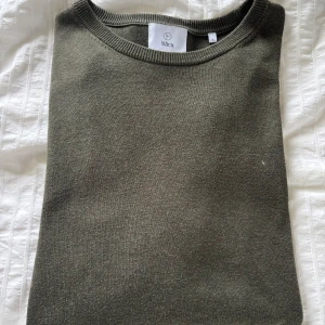 Olivgrön stickad tröja från Bläck - En stilren olivgrön stickad tröja från Bläck med rund halsringning och långa ärmar. Skick:10/10. Skriv för fler frågor