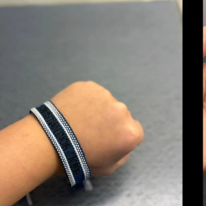 Blå Christian Dior Friendship-armband - Snyggt blått och vitt friendship-armband från Christian Dior med broderad logga. Armbandet har en klassisk, rak form och är gjort i textil med knytning i ändarna. Perfekt för dig som vill ha en cool designeraccessoar med statement.