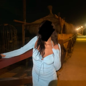 Ljusblå långärmad omlottklänning - Supersnygg ljusblå kortklänning med lång ärm och djup v-ringning. Klänningen har omlottdetalj med knyt framtill och öppen rygg. Tight passform som framhäver figuren och ger en trendig look. Perfekt för dig som vill sticka ut med en fräsch och modern stil.