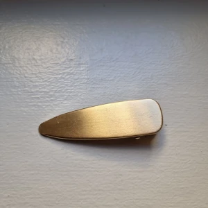 Guldigt hårspänne i metall - Snyggt hårspänne i guldigt metall med stilren, avlång form.