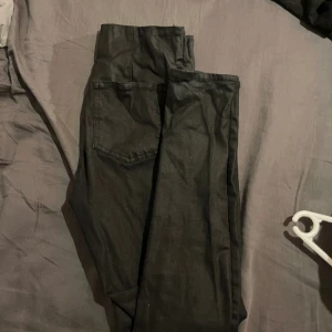 Svarta byxor med dragkedjor - Säljer ett par svarta byxor med snygga silverfärgade dragkedjor vid bensluten. Byxorna har en rak passform och är tillverkade i ett mjukt material som känns bekvämt mot huden. Perfekt för dig som gillar detaljer och vill ha en cool look.