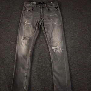 Replay Grover grå jeans, straight fit - Snygga grå Replay Grover jeans i straight fit med slitna detaljer och trasiga partier på benen för en cool, edgy look. Klassisk femficksmodell med svarta sömmar och Replay-logga på insidan. Perfekt för dig som gillar streetstyle. Priset är inte spikat!🤝