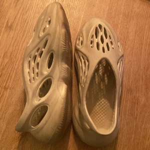 Beige adidas Yeezy Foam Runner - Säljer ett par beige adidas Yeezy Foam Runner med futuristisk design och massor av hål för extra ventilation. Skorna är tillverkade i lätt syntetmaterial och har en chunky, vågig sula. Perfekta för dig som gillar streetwear och vill sticka ut.