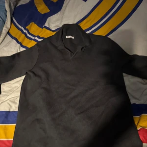 Svart polotröja från ZARA - Svart polotröja från ZARA med klassisk krage och långärmad design. Tröjan är stickad i mjukt material och har en enkel, stilren look som passar perfekt till jeans eller chinos. Perfekt för dig som gillar minimalistisk stil och vill ha något som funkar året runt.