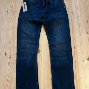 Lee Blake W32 L32 - Snygga mörkblå jeans från Lee i modellen Blake. Klassisk femficksdesign med raka ben och subtila slitningar framtill. Jeansen är tillverkade i bomull och har en normal passform som funkar till många olika stilar.
