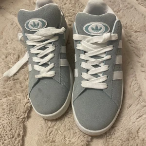 Adidas Campus sneakers ljusblå mocka - Snygga Adidas Campus sneakers i ljusblå mocka med klassiska vita ränder och vit sula. Skorna har en liten fläck annars är de helt nya 🙌🏼😌