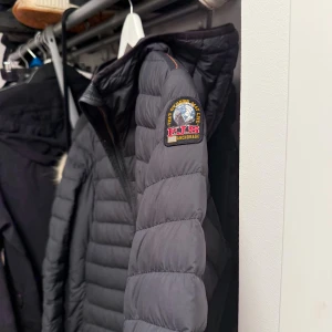 Svart dunjacka från Parajumpers M - Säljer en svart dunjacka från Parajumpers i storlek M. Jackan är superlätt, har quiltad design och snygg patch på ärmen. Insidan är ljusgrå med orange detaljer och dragkedja framtill. Perfekt för dig som vill ha en stilren och funktionell jacka. Priset diskuteras vid snabb och smidig affär 