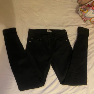 Svarta skinny jeans från 157 - Svarta jeans från 157 med skinny passform. Klassisk femficksmodell och smal siluett som sitter tight hela vägen ner. Jeansen har silverfärgade nitar och är tillverkade i stretchigt material. Dem är mid waist i midjan 