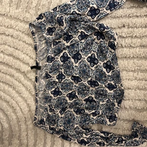 Blommiga blå-vit topp  i bomull - Snygg topp med blommigt mönster i marinblått och vitt, tillverkade i mjuk bomull. De har elastisk midja och en loose passform som gör dem sköna att bära. Perfekta för varma dagar och ger en chill vibe till din outfit.